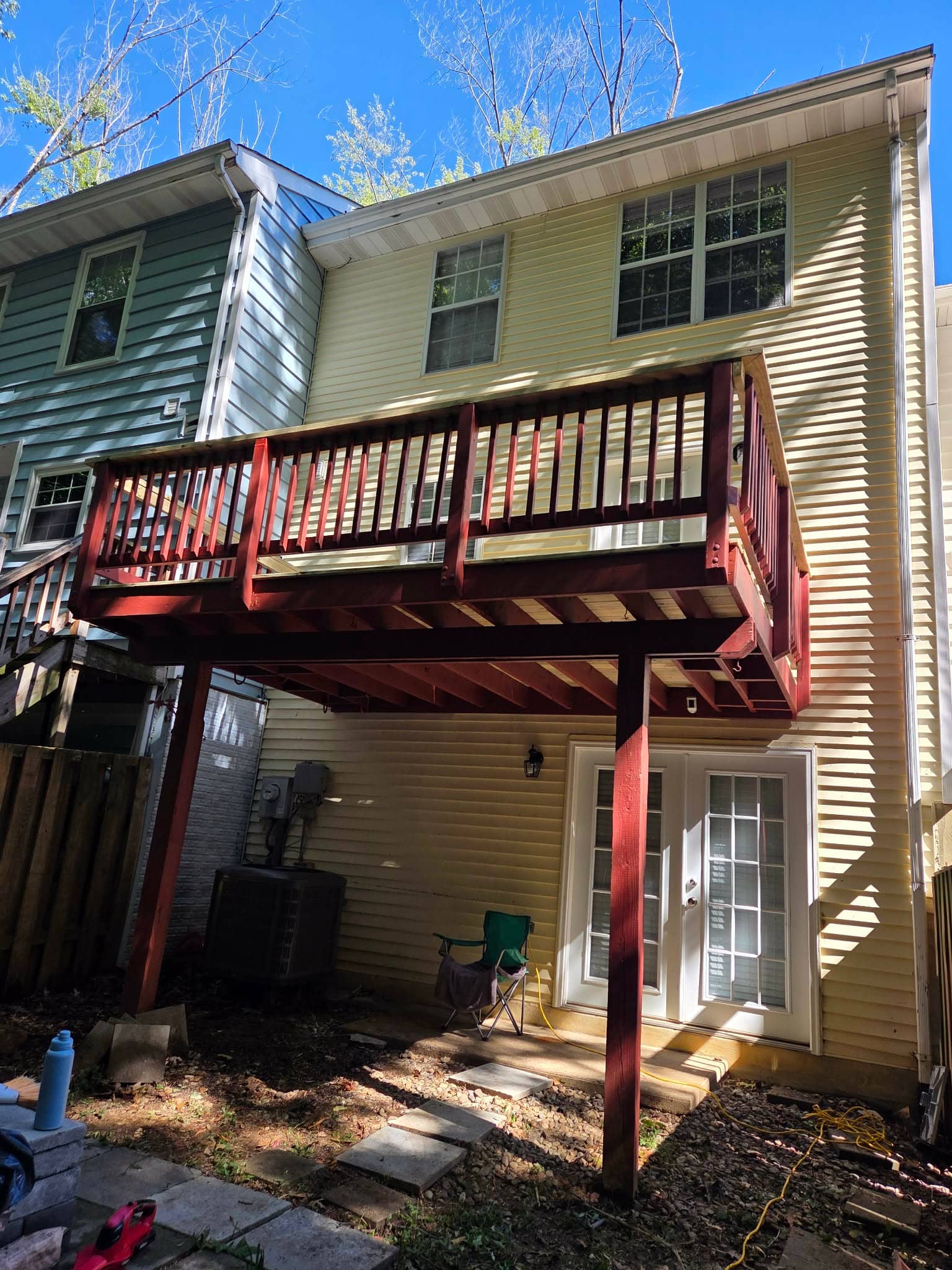 Exterior view of an elevated red wood deck attached to a townhouse.
