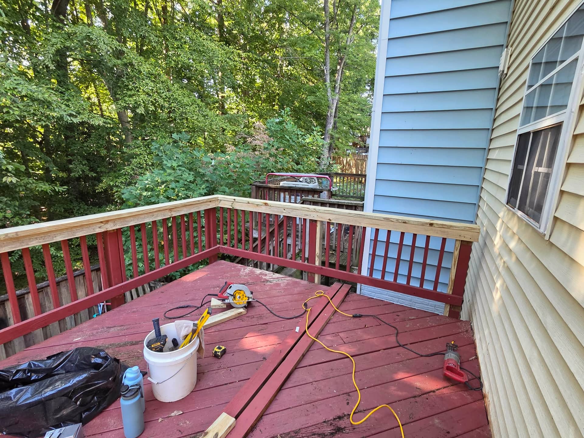 New wood top rails installed above the existing red deck balusters.